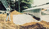 Fill dirt was added until we reached a level about 1-1/2 feet below the edge of the roof on the back of the building. We then laid a 6-foot-wide sheet of 4-mil polyethylene along the entire length of the building, to prevent water draining off the roof from running directly down along the wall.